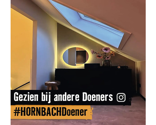 Zolderkamer met een dakraam, ronde spiegel en donker dressoir.