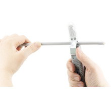 Twee handen gebruiken een kabelstripper op een kabel.