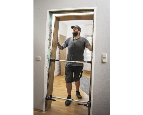 Een man monteert een deur met een deurspreider.