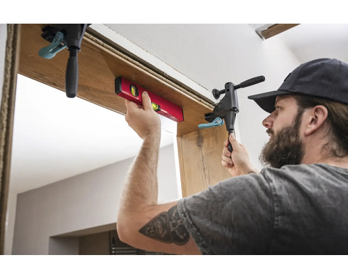 Ambachtsman monteert een deurkozijn met waterpas en lijmklem.