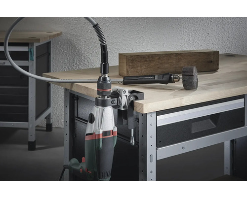 Flexibele asbevestiging met boormachine bevestigd aan een werkbank, met een stuk hout en borstelopzetstuk