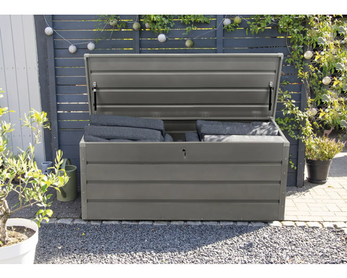 Geopende grijze tuinkist met kussens in de tuin