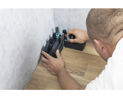 Een verstekbak wordt in een hoek op een houten vloer bevestigd.