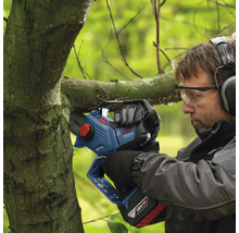 Een man snoeit een tak met een accukettingzaag.