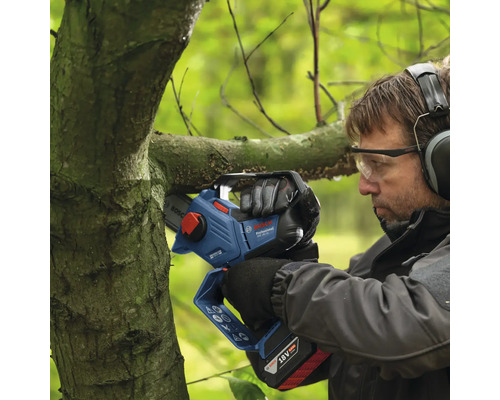 Een man snoeit een tak met een accukettingzaag.