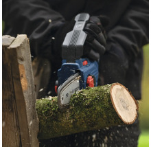 Persoon zaagt houtblok met een Bosch accu kettingzaag