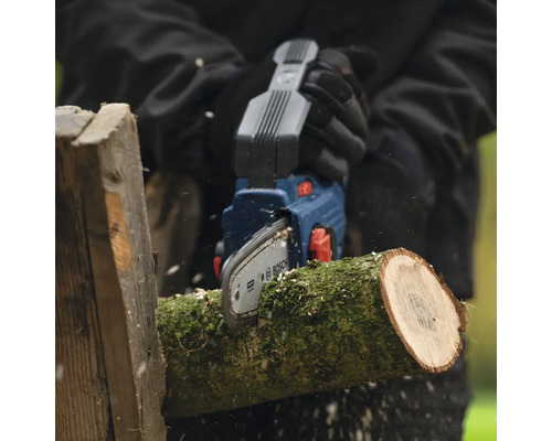 Persoon zaagt houtblok met een Bosch accu kettingzaag