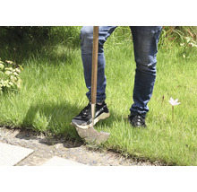 Persoon met onkruidsteker in het gras.