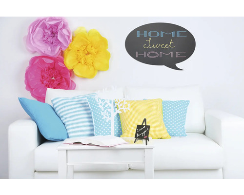 Woonkamer met witte bank, kussens, tafel, decoratie en muursticker