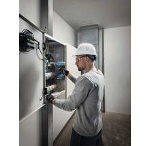 Elektricien werkt met een accuschroevendraaier aan een verdeelkast.
