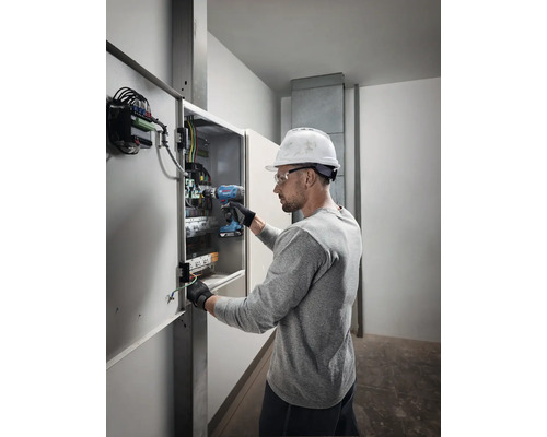 Elektricien werkt met een accuschroevendraaier aan een verdeelkast.