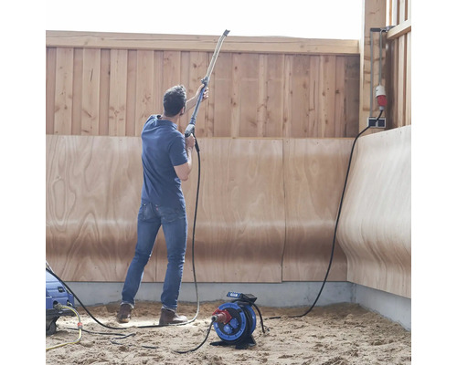Man gebruikt een hogedrukreiniger in een ruimte met houten wanden en een stroomkabelhaspel