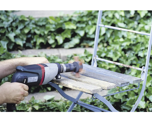 Ambachtsman schuurt een houten stoel met een boormachine en schuurkop buitenshuis.