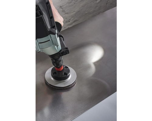 Een boormachine met een schuurhulpstuk wordt op een metalen oppervlak gebruikt.