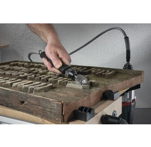 Man gebruikt een flexibele as op een houten werkstuk