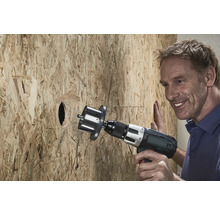 Een man boort een gat in een houten plaat met een gatzagen.