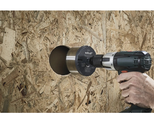 Iemand boort een gat in een houten plaat met een gatenzaag