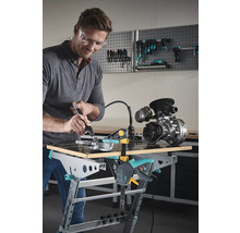 Man met veiligheidsbril bewerkt metalen onderdeel op een Wolfcraft werkbank met een multifunctioneel gereedschap.