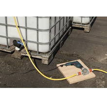 Scene met IBC-containers, een boormachine en een slangenpomp op een plank.