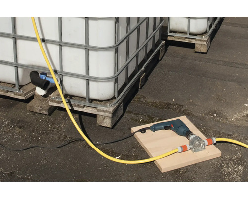 Scene met IBC-containers, een boormachine en een slangenpomp op een plank.