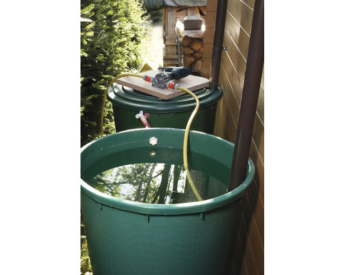 Twee groene regentonnen met waterpomp en slang in de tuin.