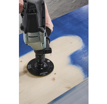 Iemand gebruikt een schuurmachine om verf van een houten plank te verwijderen.