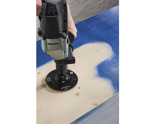 Iemand gebruikt een schuurmachine om verf van een houten plank te verwijderen.