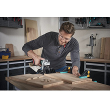 Een man gebruikt een lamellenfrees op houten planken in een werkplaats.
