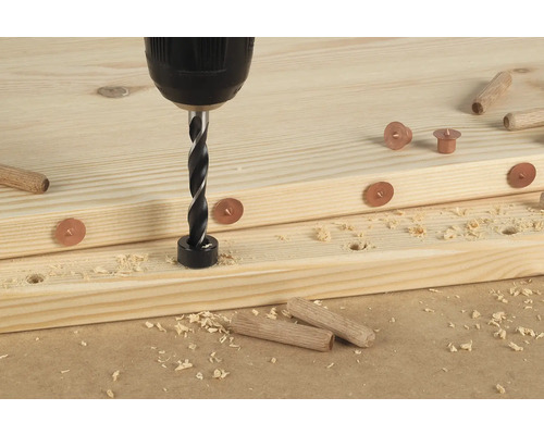 Boormachine met deuvelboor boort gat in een houten plank met markeringen