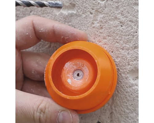 Close-up van een persoon die werkt met een boor en een oranje stofkap