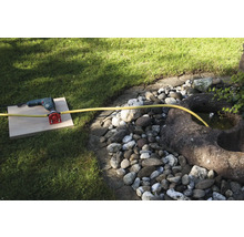 Een boormachine met wateraansluiting en slang in de tuin.