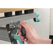 Iemand bevestigt een schroef met een schroevendraaier aan een metalen bedframe.