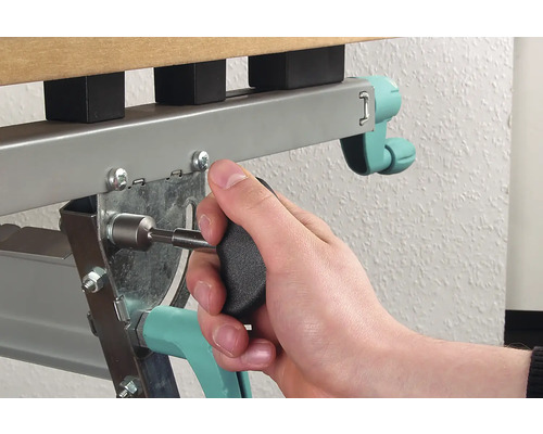 Iemand bevestigt een schroef met een schroevendraaier aan een metalen bedframe.