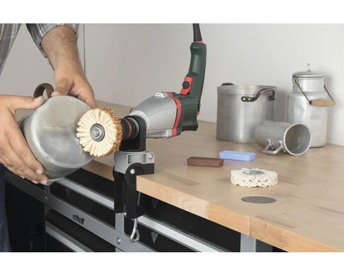 Iemand polijst een container met een polijstmachine op een werkbank.