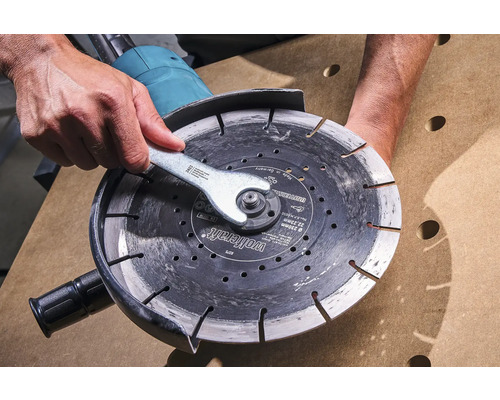 Persoon verwisselt doorslijpschijf met moersleutel op een haakse slijper