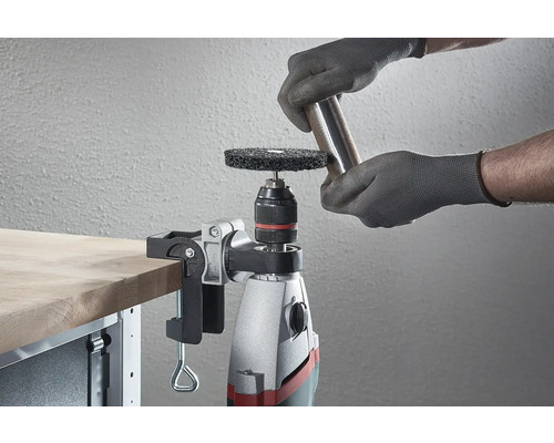 Een boormachine met een schuurschijf en werkstuk op een werkbank.