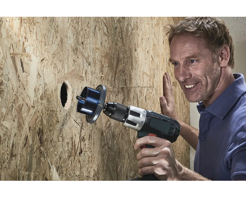 Man boort met een gatenzaag een gat in een houten wand.