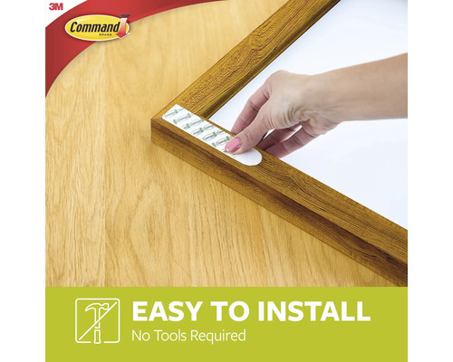 Een fotolijst wordt bevestigd met plakstrips. Command logo.