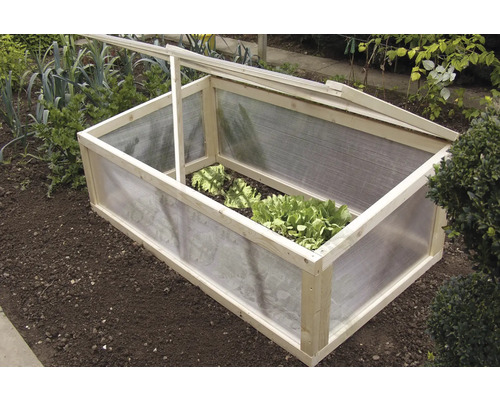 Houten en kunststof koude bak in een tuinbed met sla planten