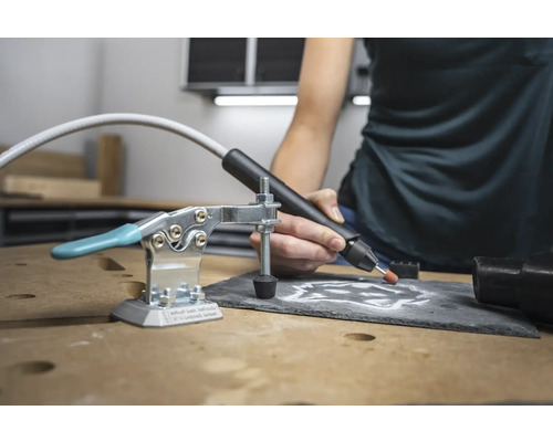 Werktafelscène met graveermachine, schroefklem en bewerkte leisteenplaat