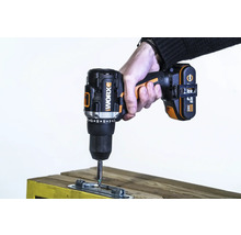 Een draadloze accuschroevendraaier van het merk Worx wordt gebruikt om een metalen plaat aan een stuk hout te bevestigen.
