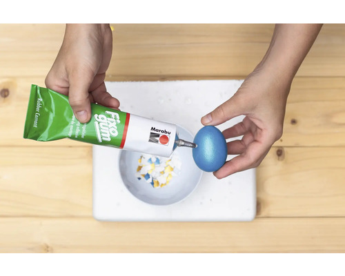 Een persoon bevestigt met lijm mozaïekstukjes op een paasei.