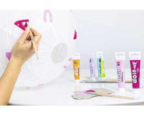 Iemand beschildert een papieren lantaarn met knutselverf.