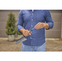 Een persoon sluit een borstel aan op een tuinslang