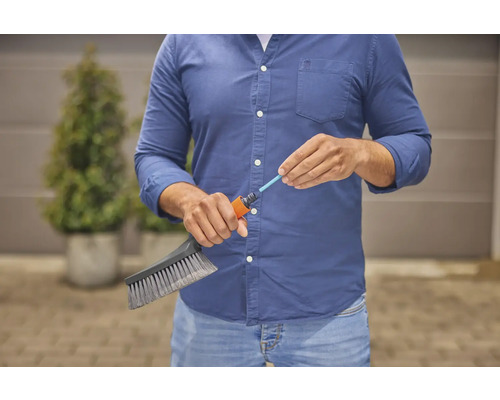 Een persoon sluit een borstel aan op een tuinslang