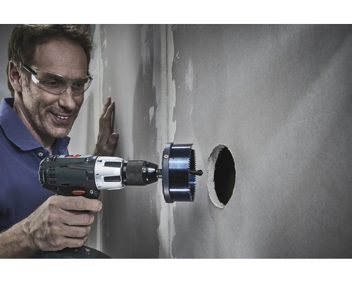 Man boort met een gatenzaag een gat in een muur