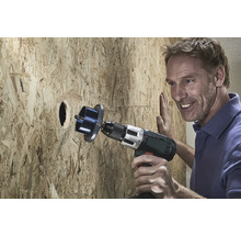 Man boort een gat in een houten plaat met een gatenzaag.