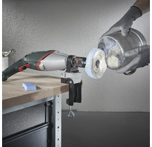 Boormachine met polijstaccessoire en bankschroef op werkbank die een metalen emmer polijst