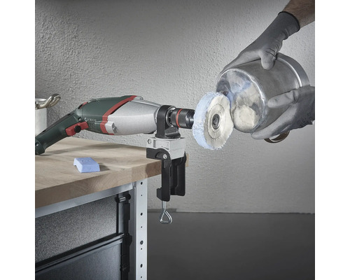 Boormachine met polijstaccessoire en bankschroef op werkbank die een metalen emmer polijst