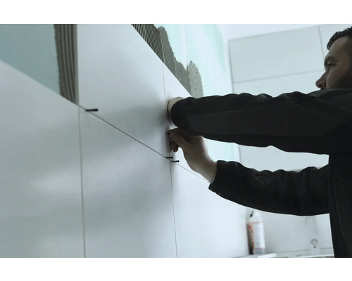 Tegelzetter aan het werk met tegels en tegeldraden